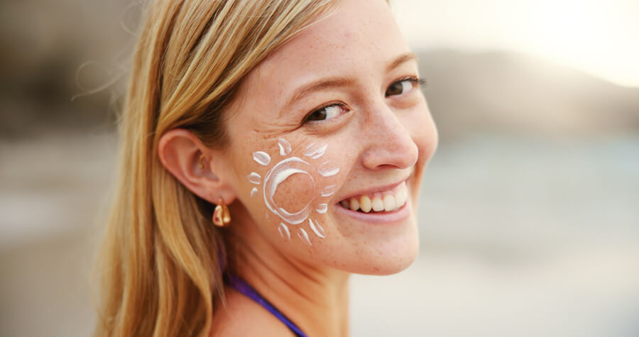 Beneficios del NCTF cuidados - Mujer sonriente con dibujo de sol en la mejilla hecho con protector solar
