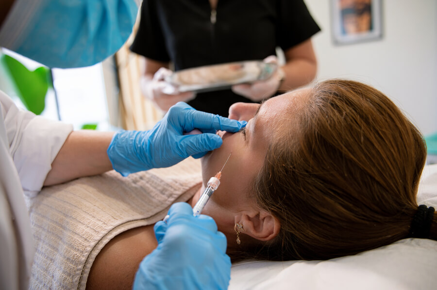 Skin booster beneficios que es - Profesional aplicando inyección estética en el rostro de una mujer.