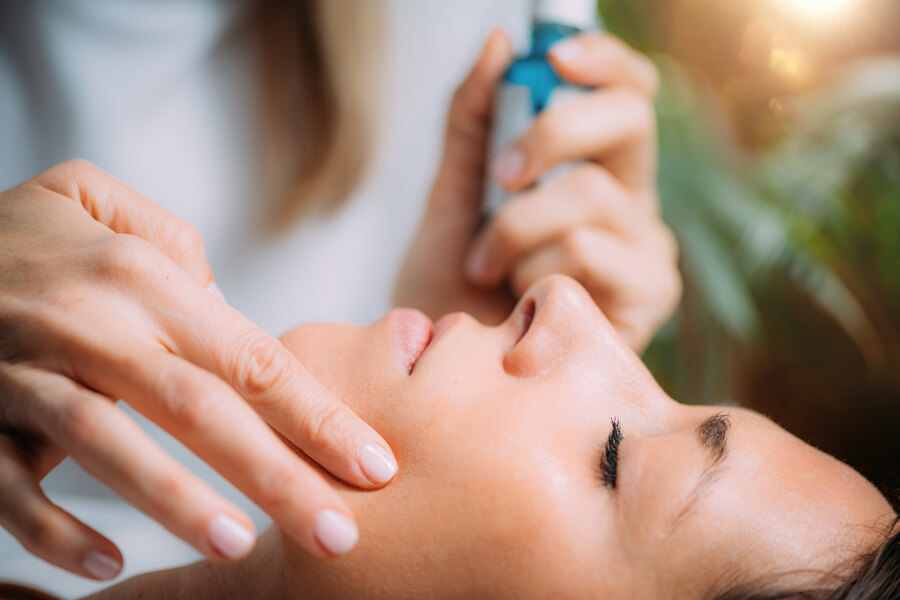Skin booster beneficios razón - Aplicación de tratamiento facial con sérum en el rostro de una mujer.