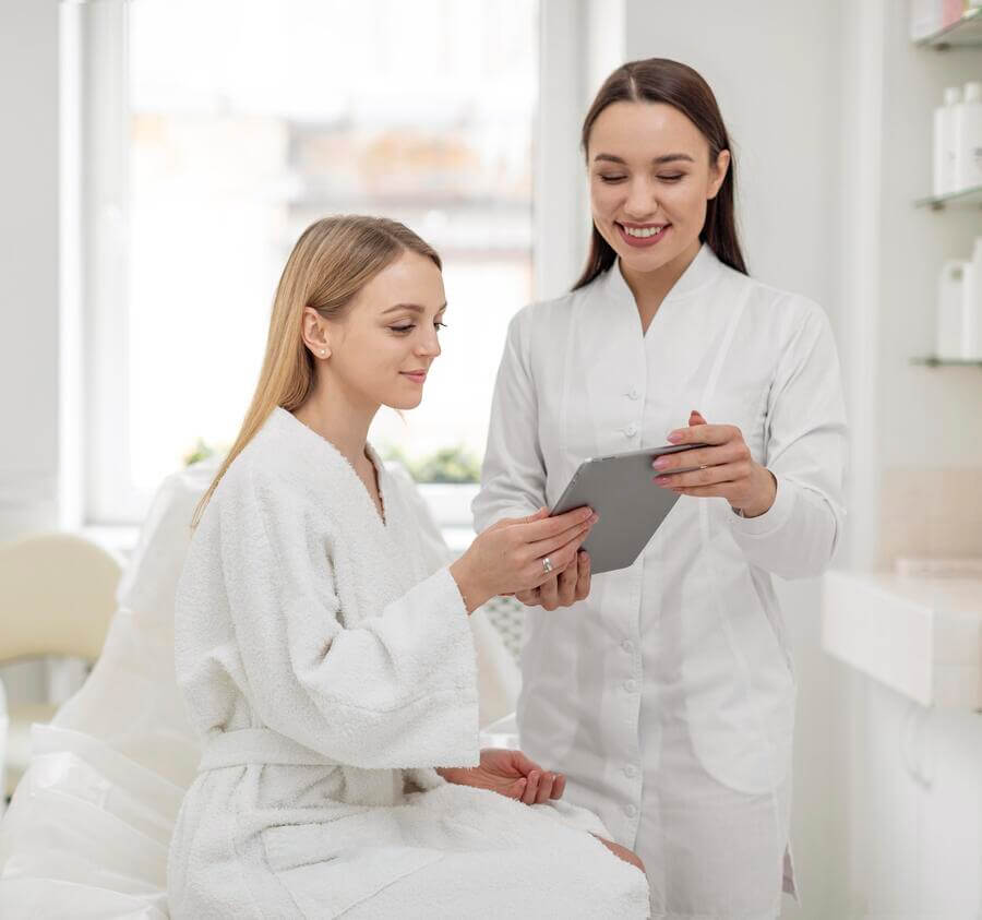 Depilación con láser bikini es segura - Especialista en estética mostrando información a una paciente en una tablet.