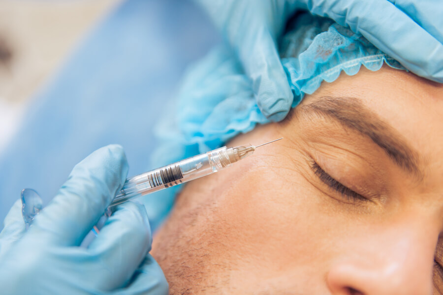 Skin booster como funciona administración - Hombre recibiendo una inyección estética cerca del ojo.