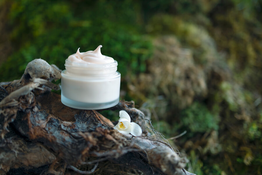 Skin booster como funciona cuidados - Tarro de crema cosmética sobre tronco con fondo natural.