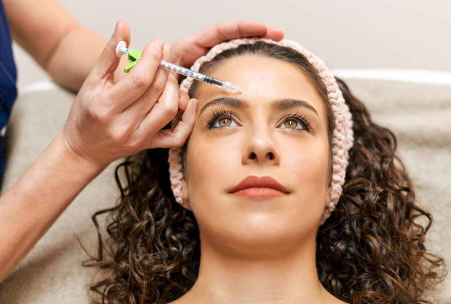 Skin booster como funciona que es - Mujer recibiendo una inyección estética en la frente.