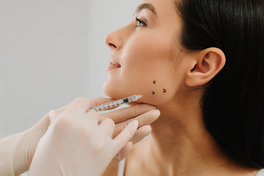 Mujer durante evaluación estética facial con marcaciones en la mandíbula y el mentón.