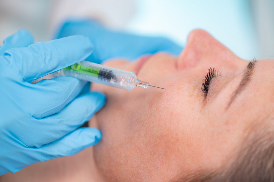 Bótox para la cara que es - Aplicación de inyección estética en el pómulo de una mujer por profesional con guantes