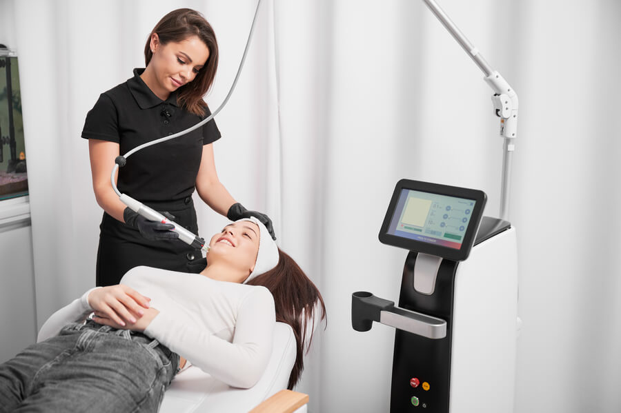 laser co2 fraccionado antes y después que es - Mujer recibiendo tratamiento facial con equipo de tecnología estética.
