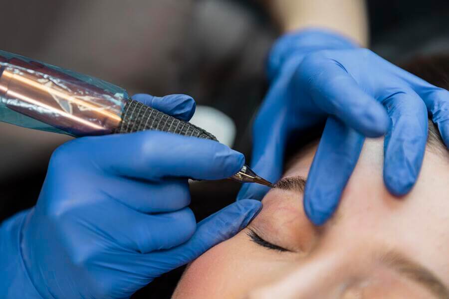Procedimiento de microblading en cejas con máquina especializada.
