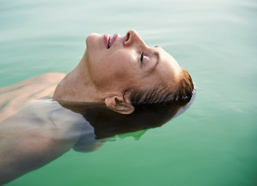 Sculptra que es - Mujer flotando relajada en el agua con los ojos cerrados.