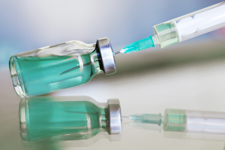 Que es bótox - Jeringa extrayendo líquido de un vial transparente con tapa metálica.